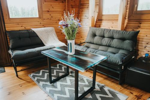 a living room with couches and a table with flowers on it at Floating guest house Musters in Paķules