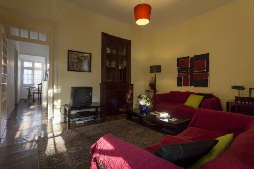 a living room with a red couch and a tv at Family House Garden in Ponta Delgada