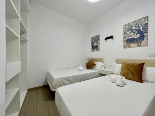twee bedden in een kamer met witte muren bij El Umbral de Muñices in Córdoba