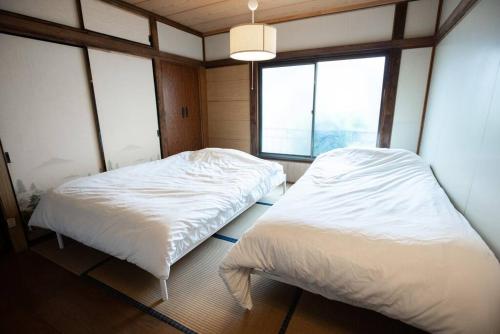 two beds in a small room with windows at 【70平米 長期予約大歓迎】6LDK/日本家屋貸切/大人数で寛げる空間 in Tokyo