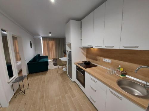 cocina con armarios blancos, fregadero y sofá en New Transilvania, en Cluj-Napoca
