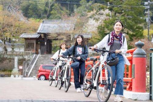 three women riding bikes down a street at Kona Stay Bicycle Resort in Izunokuni