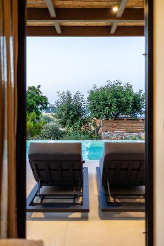 two chairs on a balcony with a view of a pool at Marni Village in Hersonissos