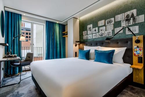 ダブリンにあるMotel One Dublinの大きなベッドと机があるホテルの部屋
