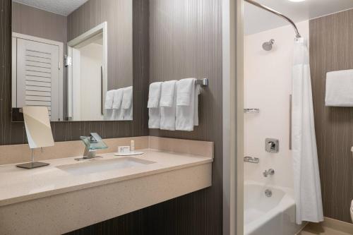 a bathroom with a sink and a mirror and a tub at Courtyard by Marriott Las Vegas Convention Center in Las Vegas