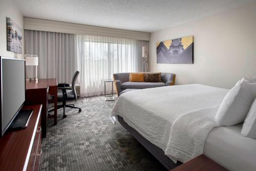 a hotel room with a bed and a desk and a couch at Courtyard by Marriott Princeton in Princeton