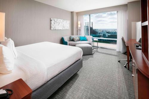 um quarto de hotel com uma cama e uma cadeira e uma janela em Courtyard Indianapolis Downtown em Indianápolis