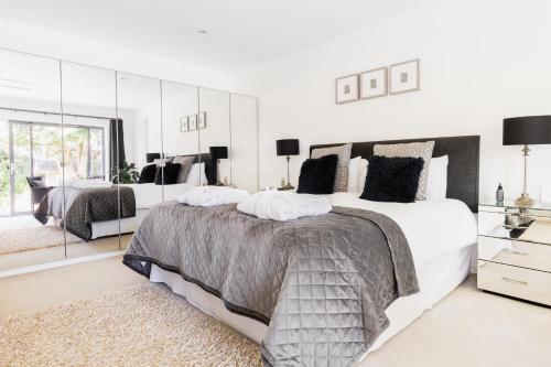 a white bedroom with two beds and a large mirror at Boswenna in St Ives