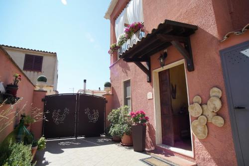un edificio rosa con un cancello e piante sopra di Domu Severino camere a Pula