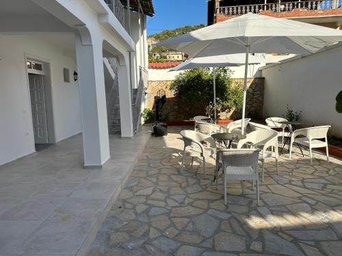 eine Terrasse mit einem Tisch, Stühlen und einem Sonnenschirm in der Unterkunft Rus Villa in Berat