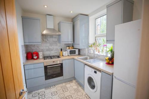 - une cuisine avec des placards bleus et un lave-linge/sèche-linge dans l'établissement Hammersmith Apollo 1 Bedroom Apartment, à Londres