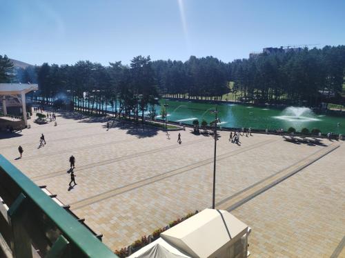 a group of people walking around a park next to a lake at Zlatibor Apartman Kraljev trg in Zlatibor