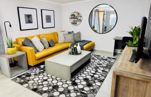 salon z żółtą kanapą i lustrem w obiekcie Lemon Ivy Guesthouse w mieście Polokwane