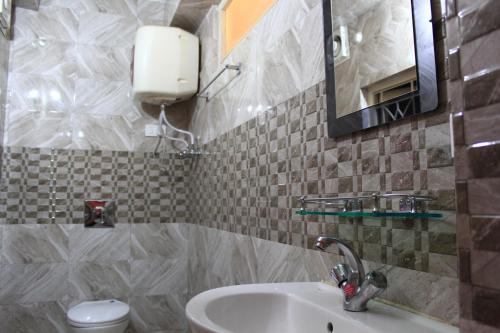 een badkamer met een wastafel, een toilet en een spiegel bij Dhe Kyi Khang by Magwave Hotels-100 Mts from MG Marg in Gangtok