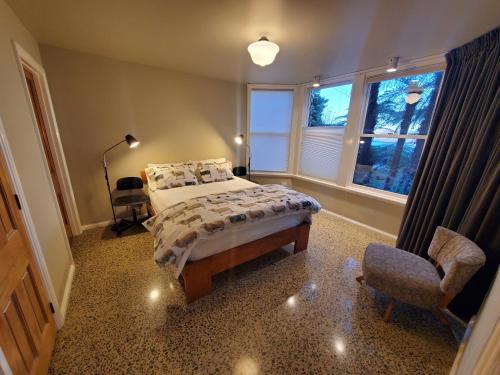 una camera con un letto e una sedia e una finestra di Koru Flat a Dunedin