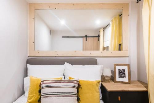 1 dormitorio con espejo sobre una cama con almohadas amarillas en Apartament Puchatek Zakopane Centrum - przytulnie en Zakopane