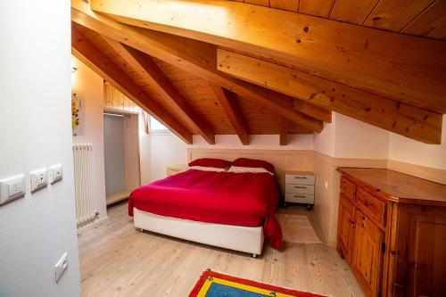 a bedroom with a red bed and wooden ceilings at Attico in centro a Folgaria in Folgaria