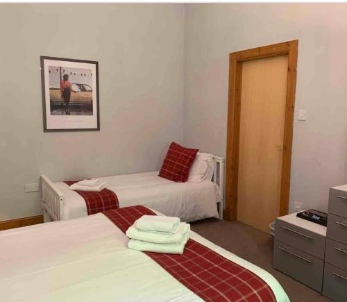 a bedroom with two beds and a dresser with towels at Chandlers Country House in Rothesay