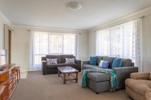 a living room with two couches and a table at Mountain Explorer - perfect base for exploring in Deloraine