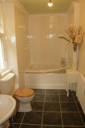 a bathroom with a tub and a toilet and a sink at Chandlers Country House in Rothesay