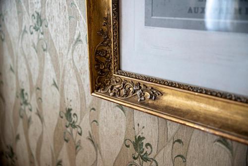 a gold picture frame on a wall with floral wallpaper at Boutique-Hotel Amalienhof in Weimar