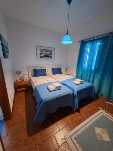 1 dormitorio con 2 camas y cortinas azules en Cycladic House in Paros en Márpissa