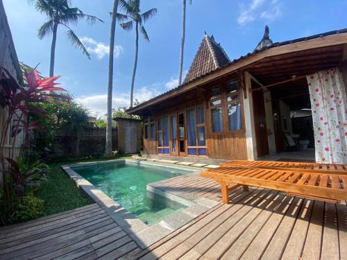 une terrasse en bois avec un banc à côté d'une maison dans l'établissement Sarini Villas, à Blahbatu