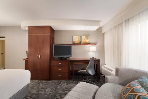 a hotel room with a bed and a desk with a television at Courtyard by Marriott Potomac Mills Woodbridge in Woodbridge