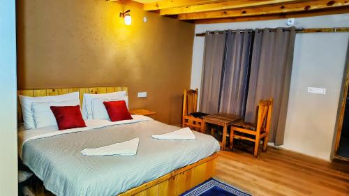 a bedroom with two beds with red pillows and a chair at Mystic Pangong in Spangmik