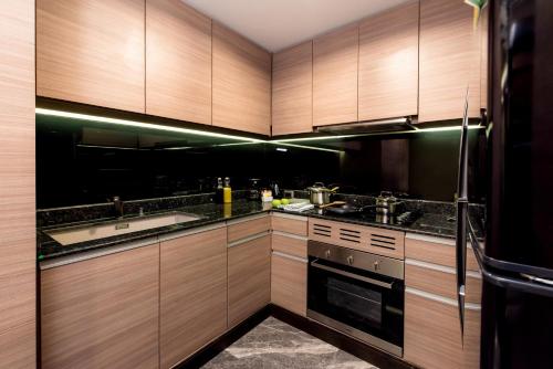 a kitchen with wooden cabinets and a sink and a stove at Qiss Residence by Bliston in Bangkok
