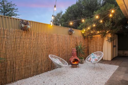 a backyard with two chairs and a vase and a fence at Perfect Cosy Beachside Escape in Grange