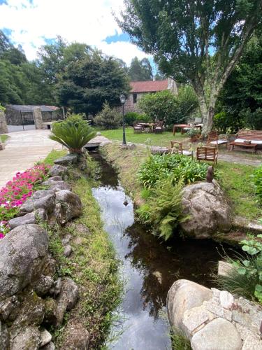 un ruscello in un giardino con rocce e fiori di Entre Os Ríos - Casa Rural y Enoturismo a A Pobra do Caramiñal