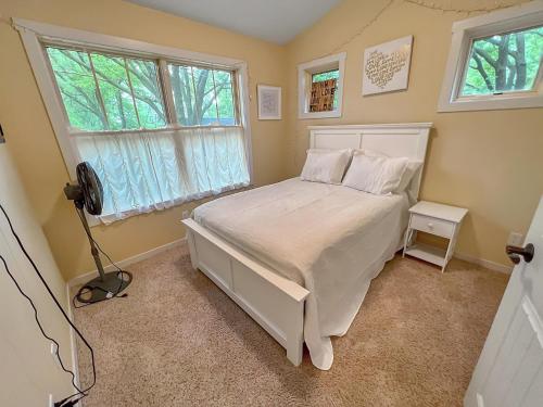 - une chambre avec un lit blanc et 2 fenêtres dans l'établissement Monarch Cove Home off West Lake, à Spirit Lake