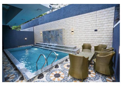 una piscina con sillas, una mesa y una chimenea en Sunflower Villa en Lonavala
