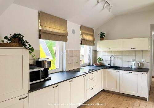 a kitchen with white cabinets and a black counter top at Apartamenty Zacisze 1 in Poddąbie