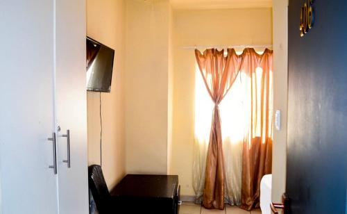 a room with a window with a chair and a television at Asmara Hotel in Johannesburg