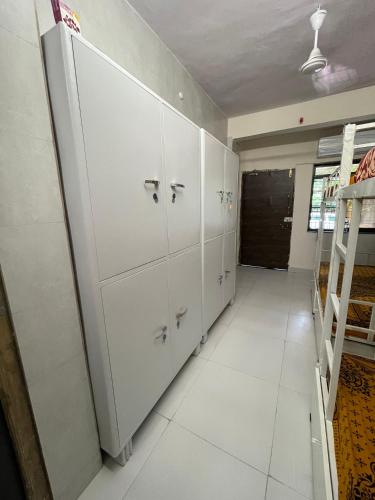 a large white locker room with white cabinets at Frostybeds Hostel Kharghar Navi Mumbai in Navi Mumbai
