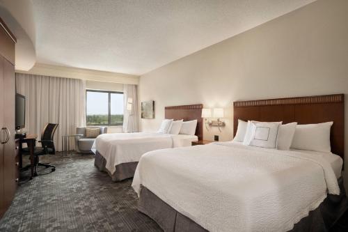 a hotel room with two beds and a desk at Courtyard by Marriott Middletown Goshen in Middletown