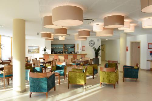 un restaurant avec des chaises, des tables et une horloge dans l'établissement Domitys Les Côteaux de l'Esterel, à Fréjus