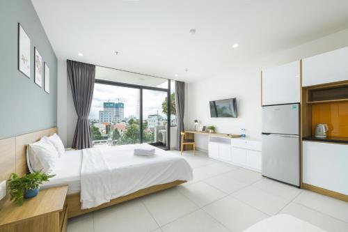 a bedroom with a white bed and a large window at The Green House - Serviced Apartment in Thu Dau Mot