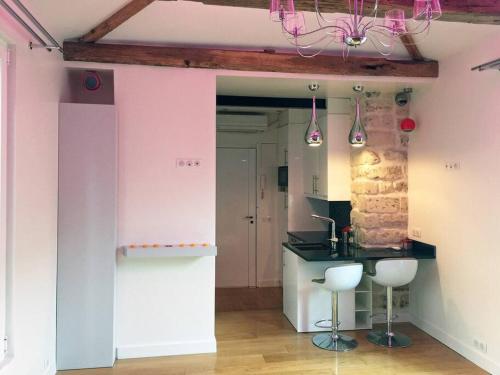 una cocina con paredes rosas, encimera y taburetes en Maisons-Alfort superbe appartement de standing, en Maisons-Alfort