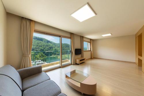 a living room with a couch and a large window at Oak Valley Resort Valley Village in Wonju