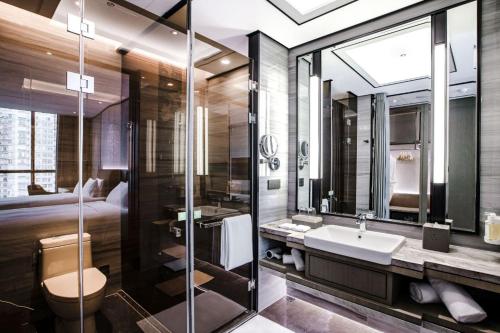 a bathroom with a sink and a toilet and a bed at Holiday Inn Taiyuan City Center in Taiyuan