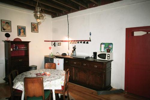 uma cozinha com uma mesa, um frigorífico, uma mesa e cadeiras em Studio Les Pourettes em Feusines