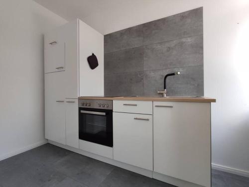 una cocina con armarios blancos y fregadero en 'BRIGHT 201' Moderne, helle Wohnung in BI Zentrum, 400 m bis Lokschuppen, Smart-TV, WLAN, en Bielefeld