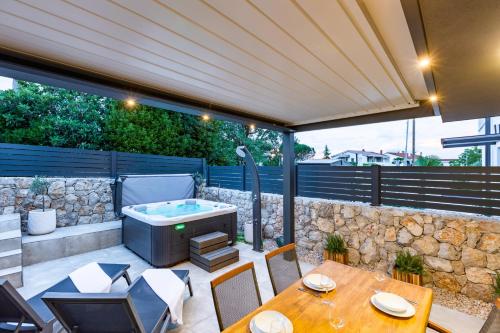 a patio with a hot tub and a table and chairs at Superior Apartments in Malinska