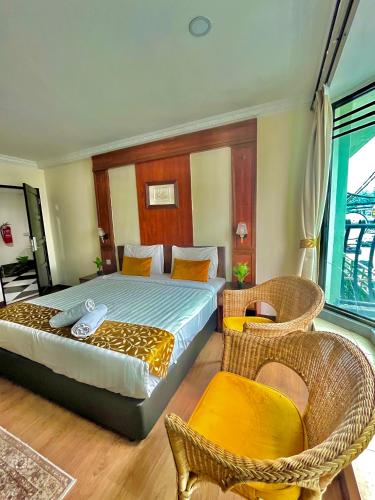 a bedroom with a bed and two wicker chairs at Melur Inn in Cameron Highlands