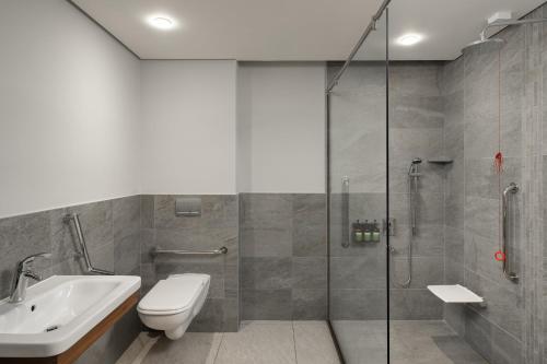a bathroom with a shower and a toilet and a sink at Crowne Plaza - Dar Es Salaam by IHG in Dar es Salaam