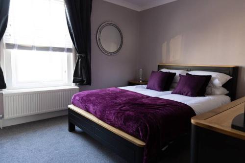 a bedroom with a large bed with a purple blanket at Rosa: Seaside home recently renovated in Portsmouth