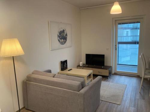 een woonkamer met een bank en een tv bij Kotimaailma Apartments Seinäjoki - Upea kaksio keskustassa in Seinäjoki